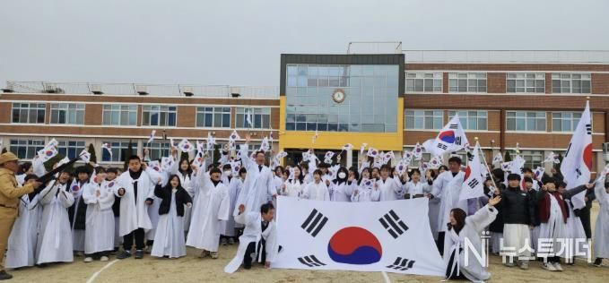 제5회 온양지역 3·11만세운동 재현행사에서 참가자들과 온양초 학생들이 대형 태극기와 함께 힘차게 만세를 외치며 기념촬영하고 있다.